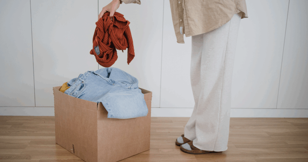 person filling up a box of clothes to donate
