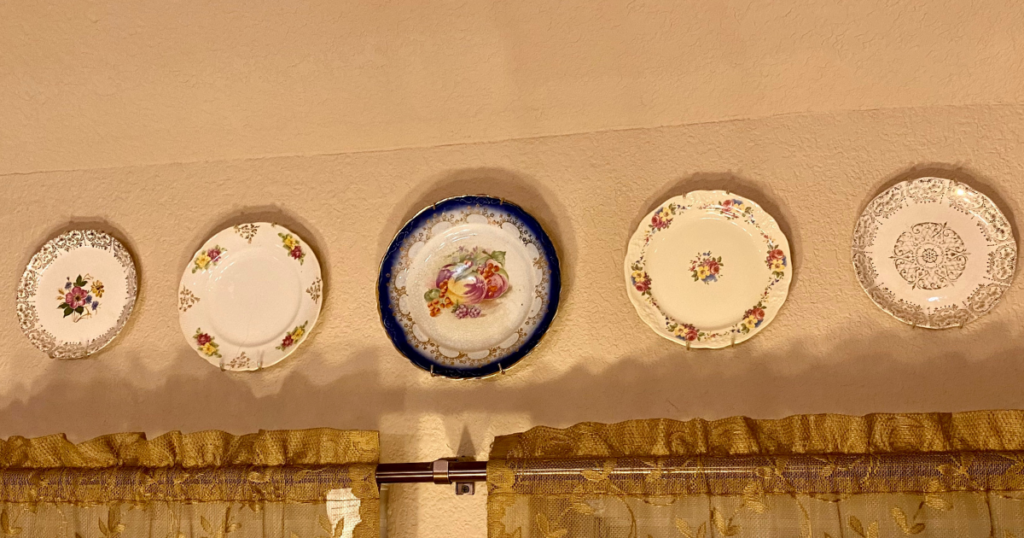 Vintage family plates displayed on a kitchen wall after shopping my home instead of buying new decor.