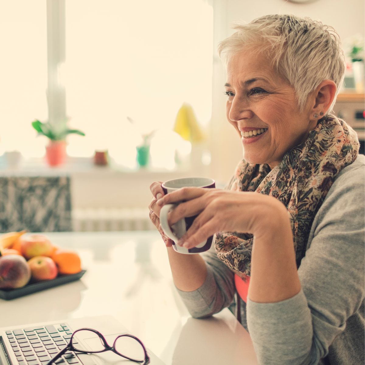 Happy woman enjoying coffee at home while using her laptop