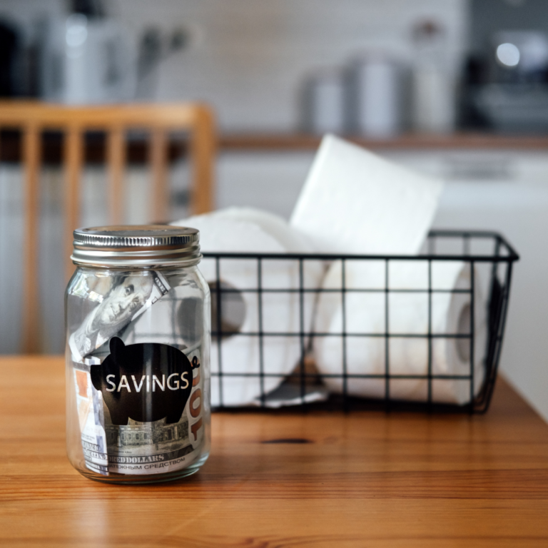 Savings jar and receipts on a kitchen table for frugal living